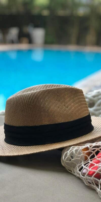 A stylish straw hat rests poolside, capturing a serene summer vibe.